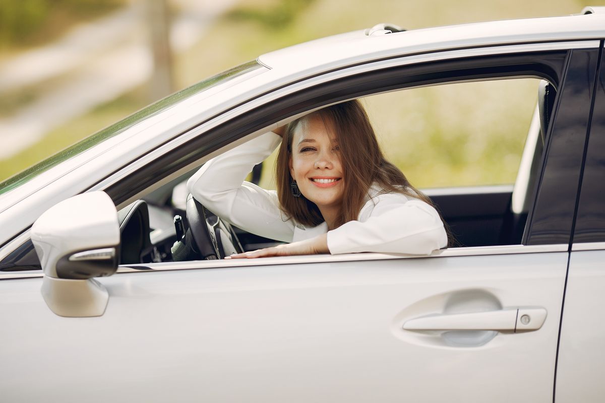 Une jeune femme souriante au volant d'une voiture à l'arrêt